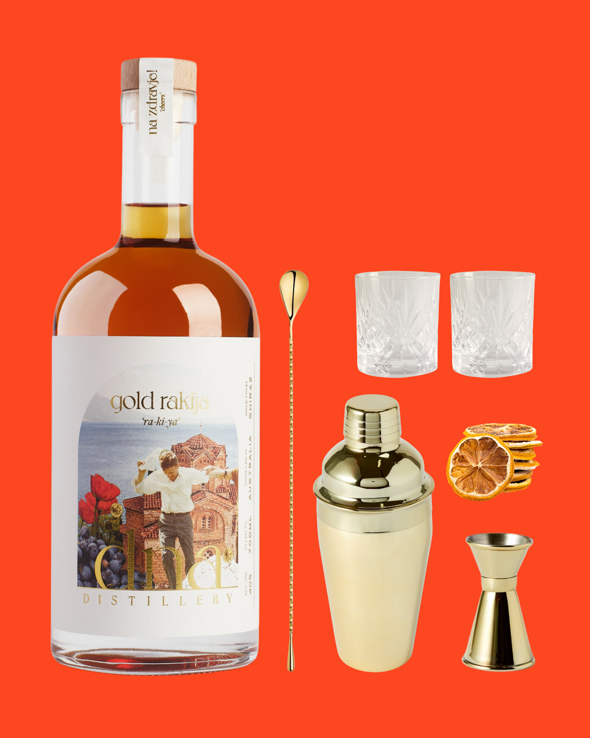 DNA Gold Rakija with two glasses, gold cocktail tools and dried citrus on the DNA red background.